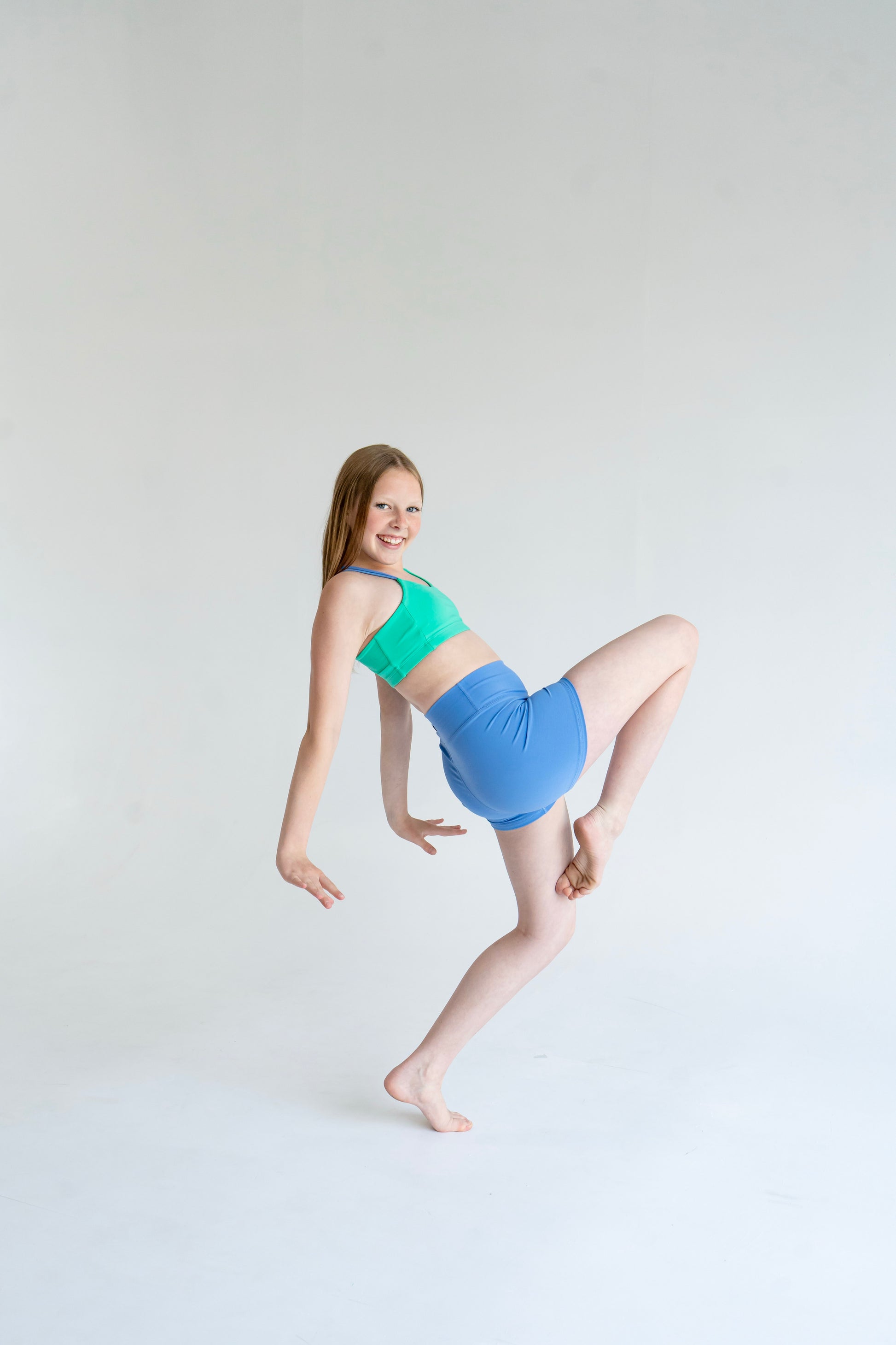 Girl in Laguna Green / Newport Blue asymmetrical dance top dance pose | Pivot Dancewear